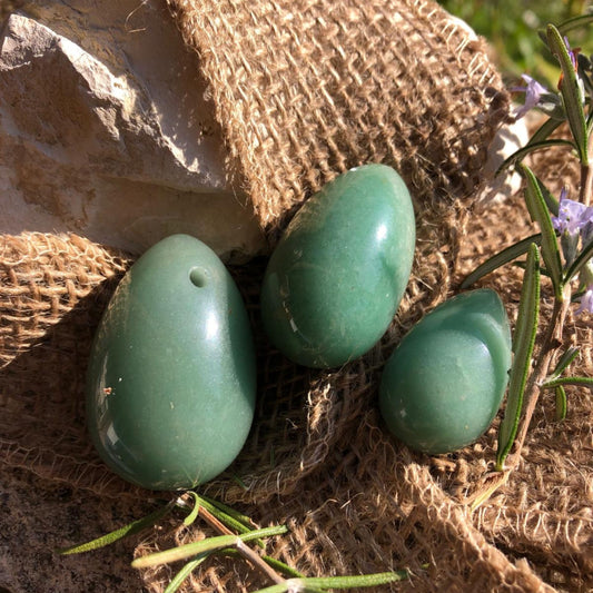 3 oeufs de Yoni en aventurine verte sont délicatement posés sur un tissu en fibre naturelle