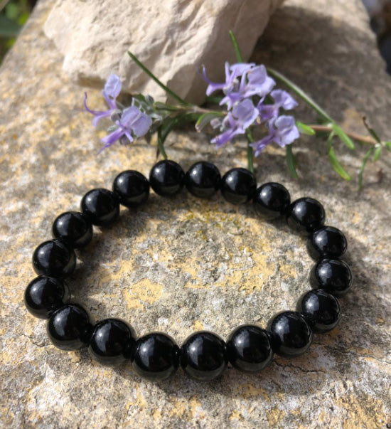 Bracelet en pierre Naturelle en Obsidienne noire devant un petit bouquet violet