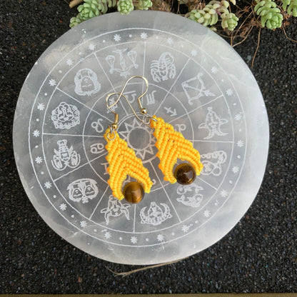 Boucles d’oreilles jaunes en macramé avec perle d’œil de tigre, accessoire spirituel favorisant la confiance et la joie de vivre.