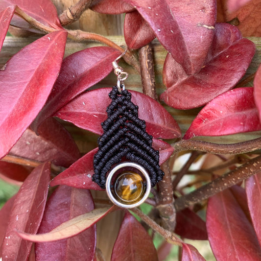 Bijou artisanal fait main en macramé noir et pierre naturelle œil de tigre, photographié dans un style bohème chic.