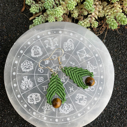 Création artisanale en micro-macramé ornée de pierres d’œil de tigre, mise en scène sur un disque en séléntite évoquant la transformation et la sérénité.